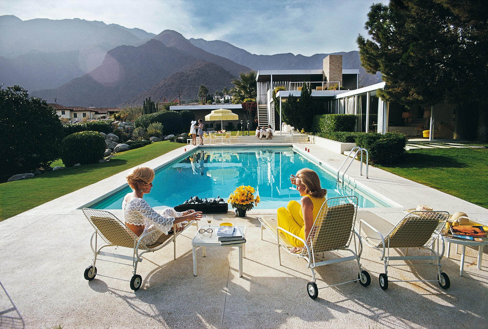 Palm Springs, Kaufman House, Two women sitting by a pool with mountains in the background