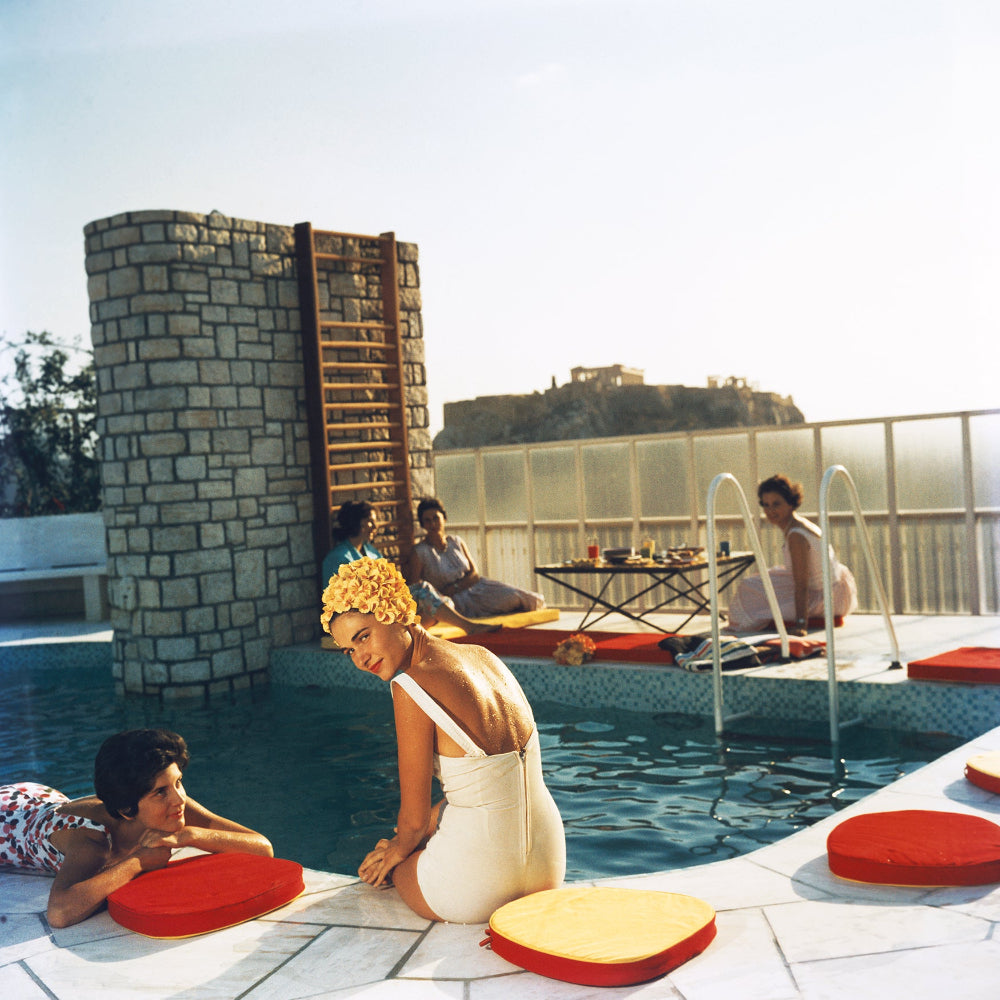 People relaxing by a pool with a scenic background