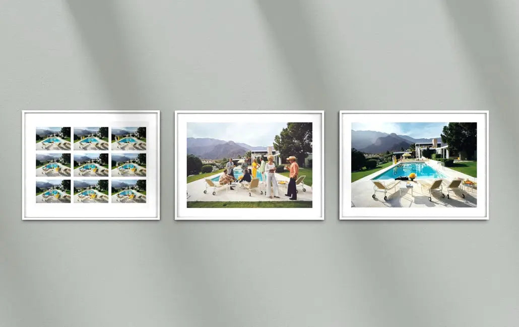 Three framed landscape and lifestyle photographs displayed side-by-side on a light gray wall with soft diagonal shadows. The left frame contains a 4x2 grid of small scenic photos, the middle frame shows a group of people standing outdoors with dogs near mountains, and the right frame shows a luxurious poolside scene with lounge chairs and mountains in the background. The Picturalist Wall Art and Photography for Designed Interiors. Slim Aarons Collection, Poolside. Getty Images Gallery.