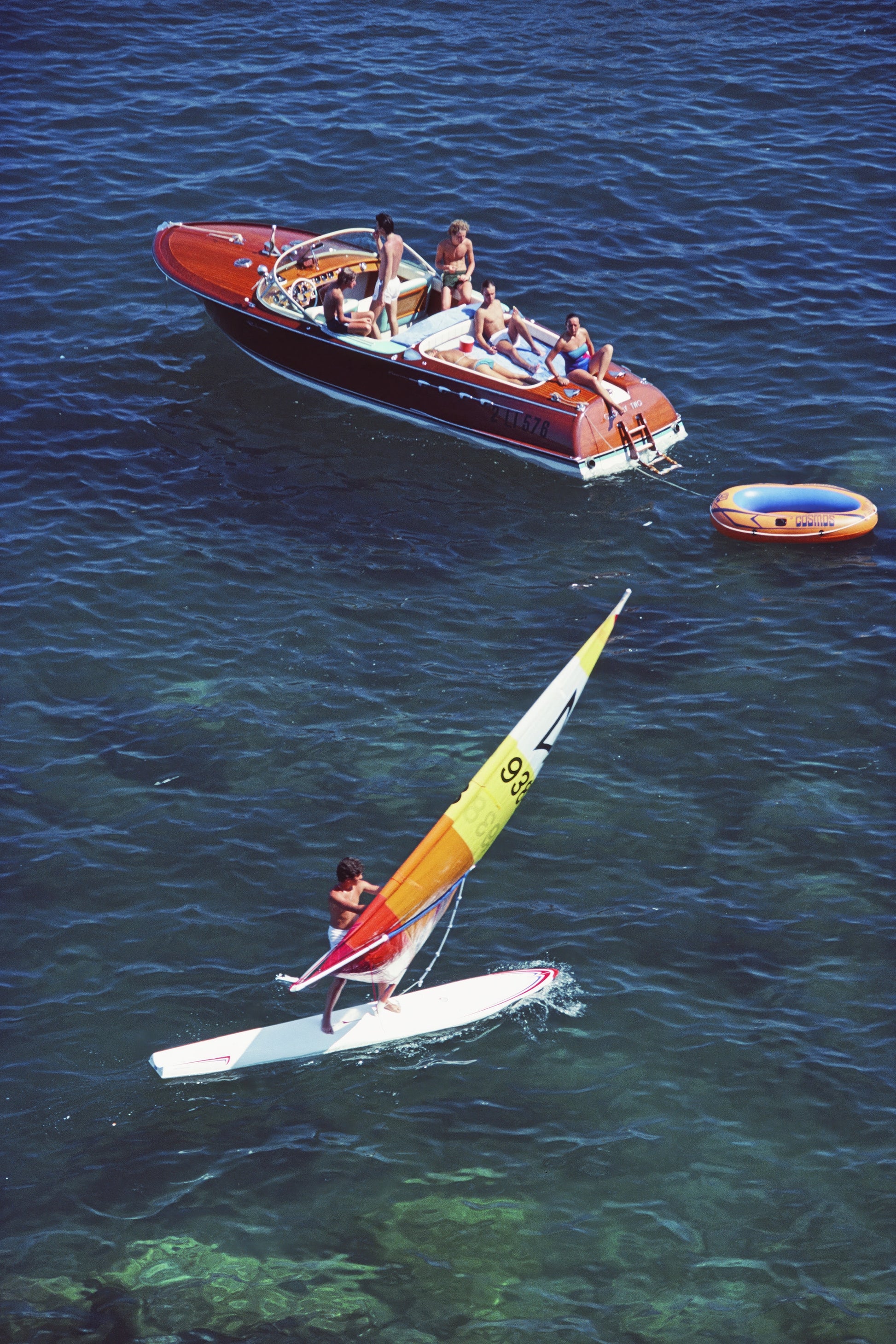 People on a boat and windsurfer in the water