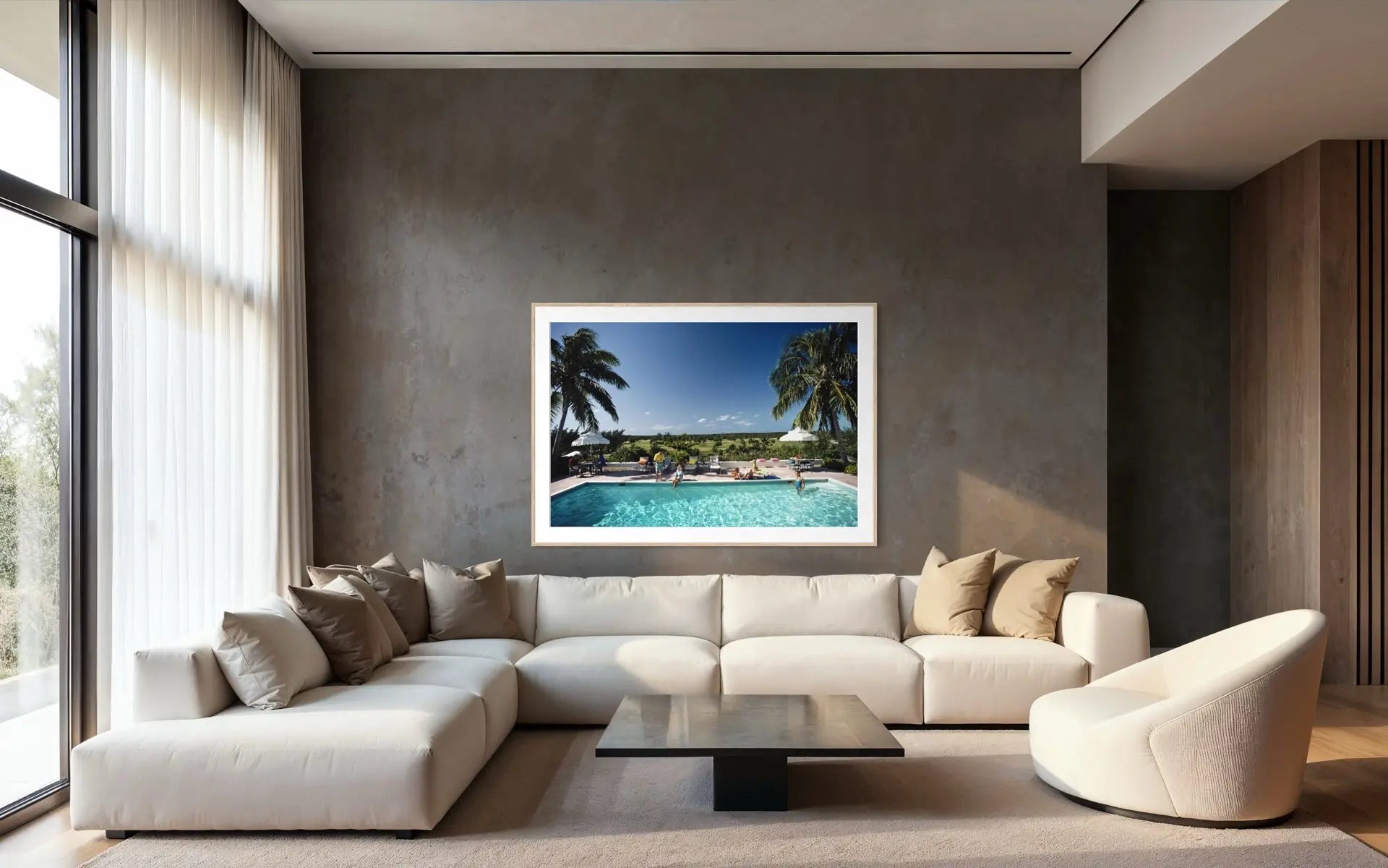 A framed tropical poolside landscape print hangs on a textured dark gray wall above a modern white sectional sofa in a contemporary living room.