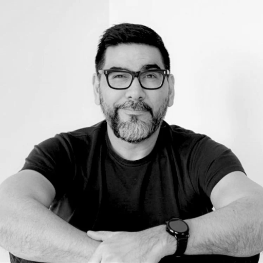 Black and white photo of a man with glasses and a beard wearing a black t-shirt.