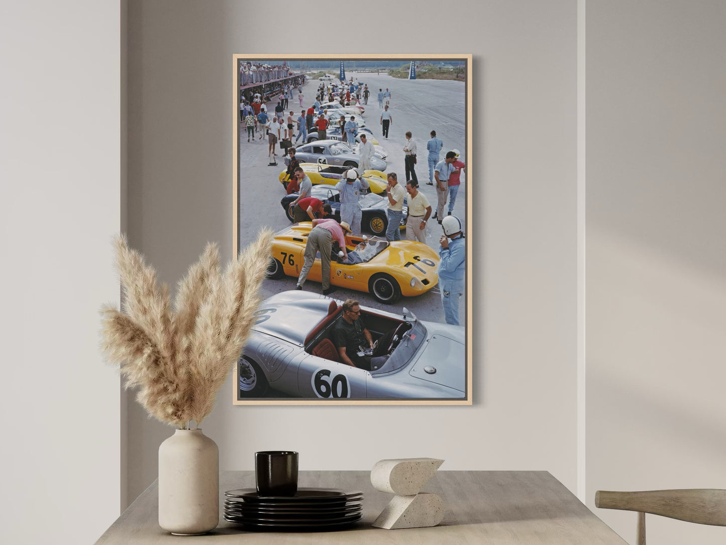 Framed poster of a race car scene on a wall above a table with decorative items.