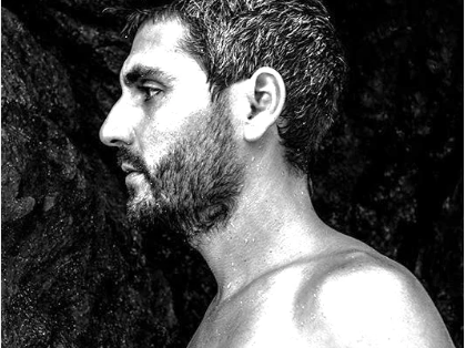 Black and white profile of a person with a beard against a dark background