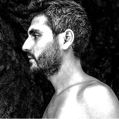 Black and white profile of a person with a beard against a dark background