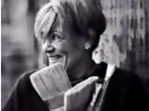 Black and white photo of a woman holding paint brushes outdoors