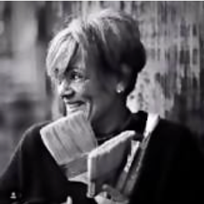 Black and white photo of a woman holding paint brushes outdoors