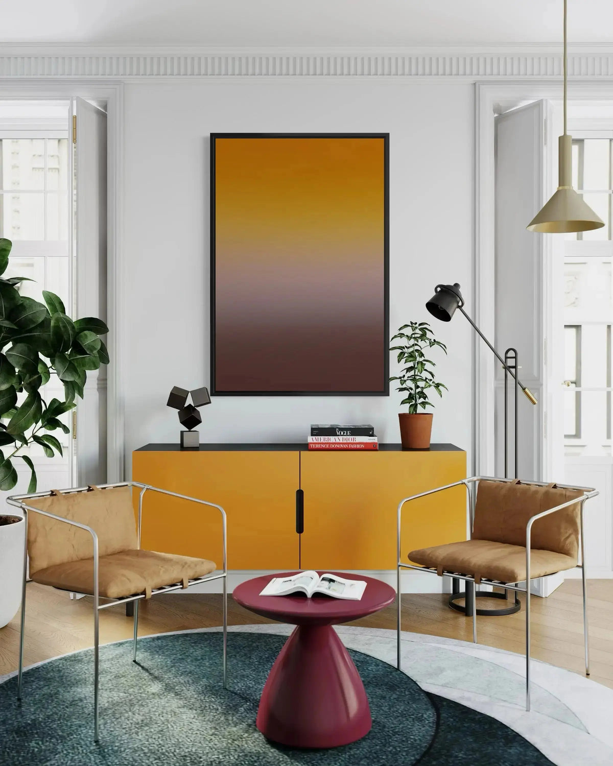 A modern living room scene featuring a large vertical framed art print with a yellow-to-brown gradient, displayed above a bright yellow cabinet. The room includes two brown upholstered armchairs with chrome frames, a small round red coffee table, and a green potted plant.