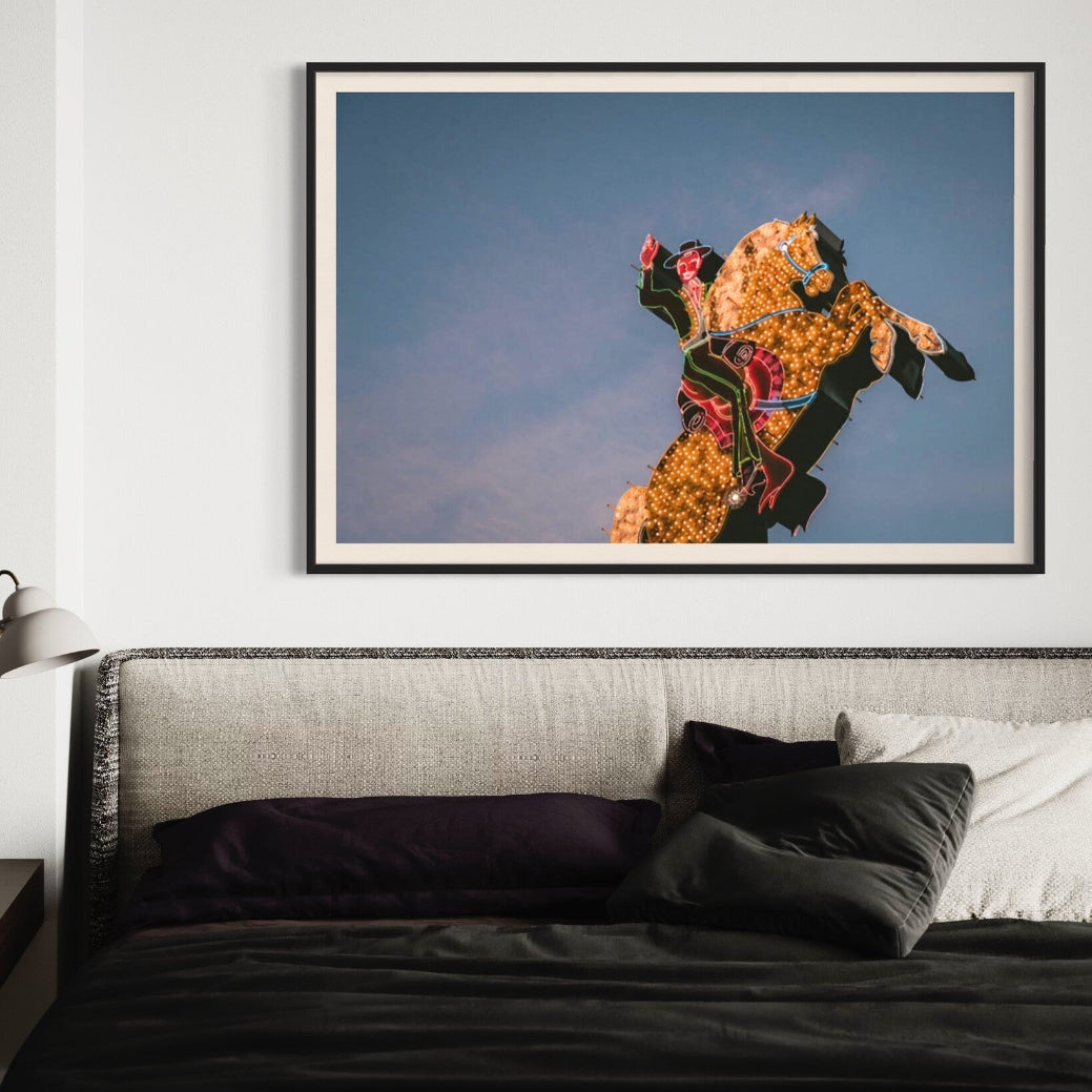 Luminous Cowboy Tale neon cowboy artwork shown above a contemporary bed setting, framed by The Picturalist.