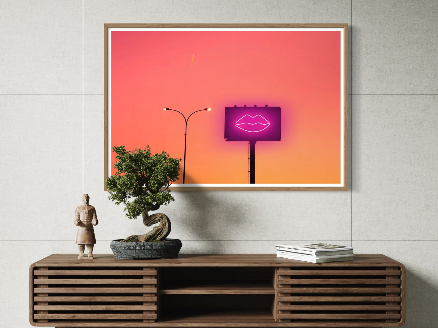 Framed artwork with a pink light bulb on a wooden console table.