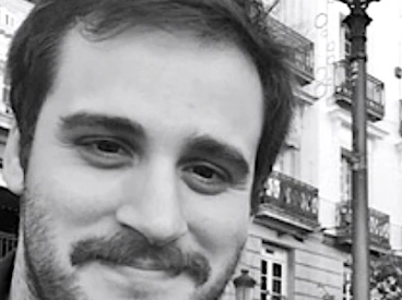 Black and white photo of a man with a beard in an urban setting