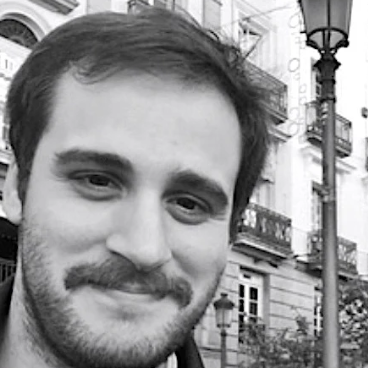 Black and white photo of a man with a beard in an urban setting