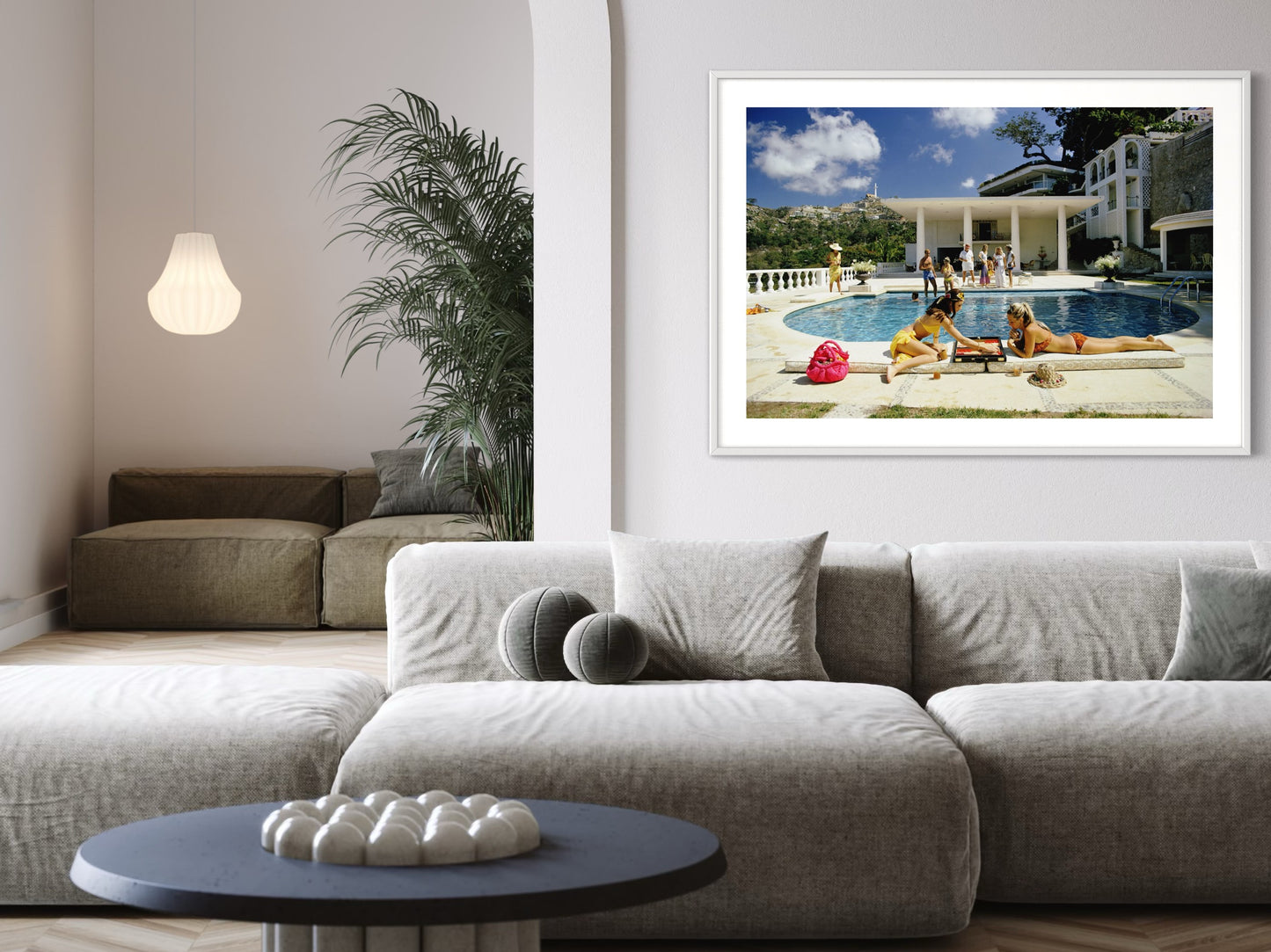 Framed photograph of people by a pool on a wall above a modern living room.