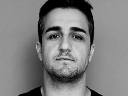 Black and white portrait of a man with short hair and stubble.