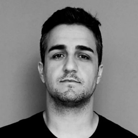 Black and white portrait of a man with short hair and stubble.