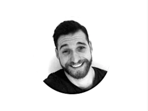 Black and white circular portrait of a smiling person with a beard.