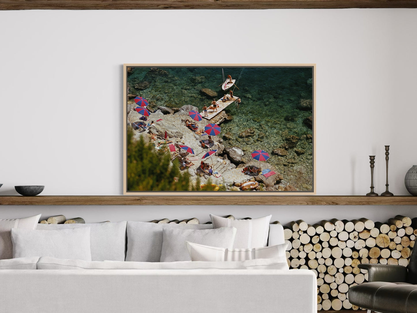 Framed artwork of people on a beach with a white wall and sofa in the background