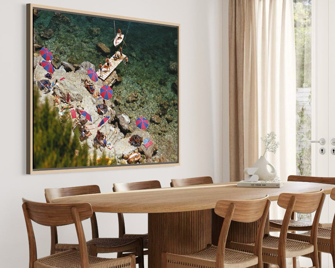 Dining room with a large framed artwork on the wall above a wooden table and chairs.