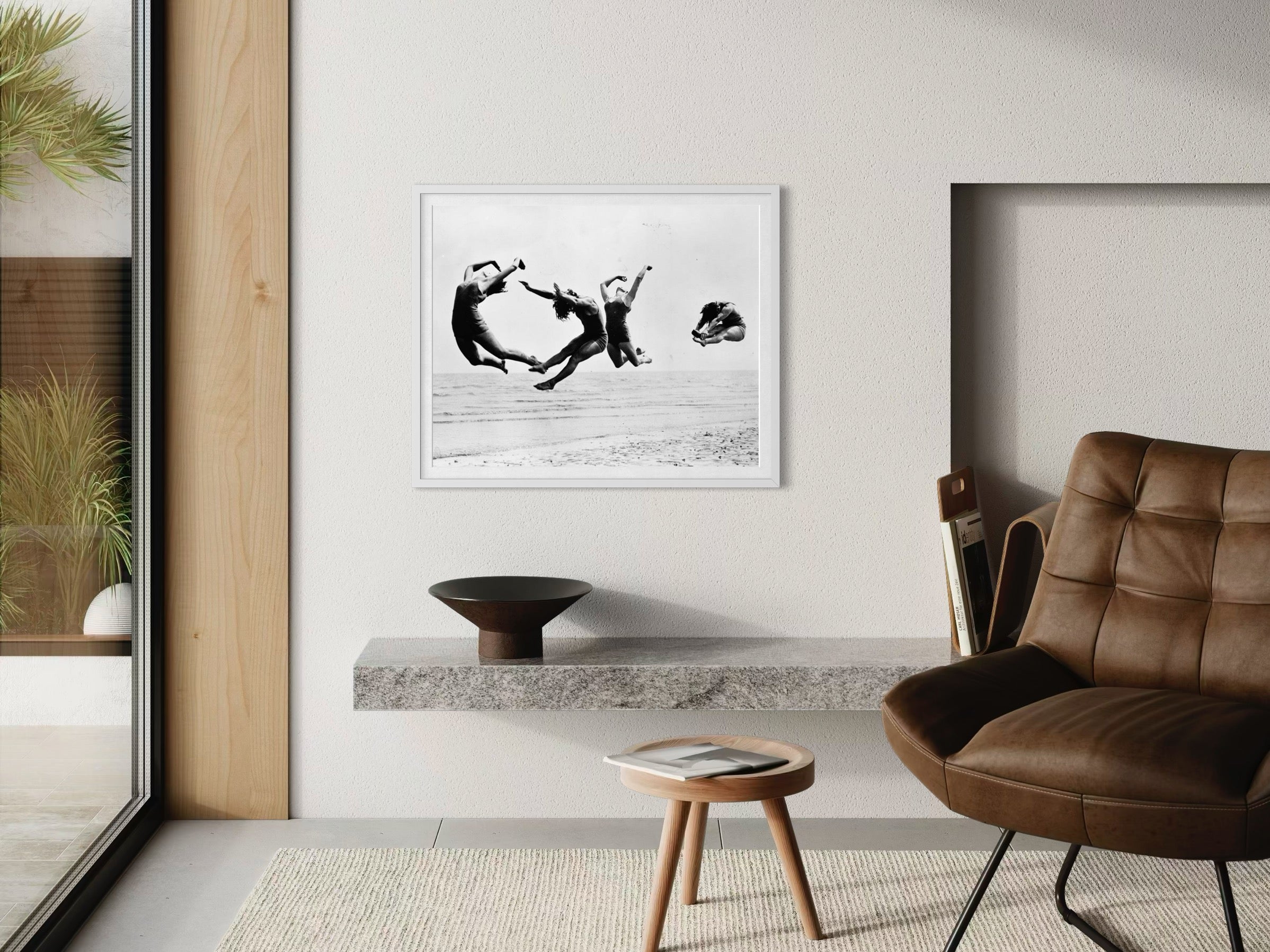 Modern interior with a brown leather chair, wooden stool, and framed black and white artwork on a wall.