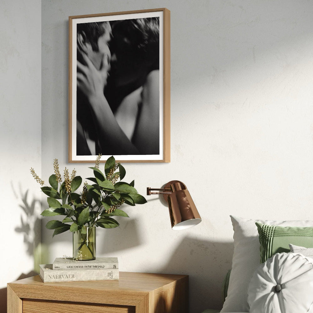 Framed artwork above a wooden nightstand with decorative items in a bedroom setting.