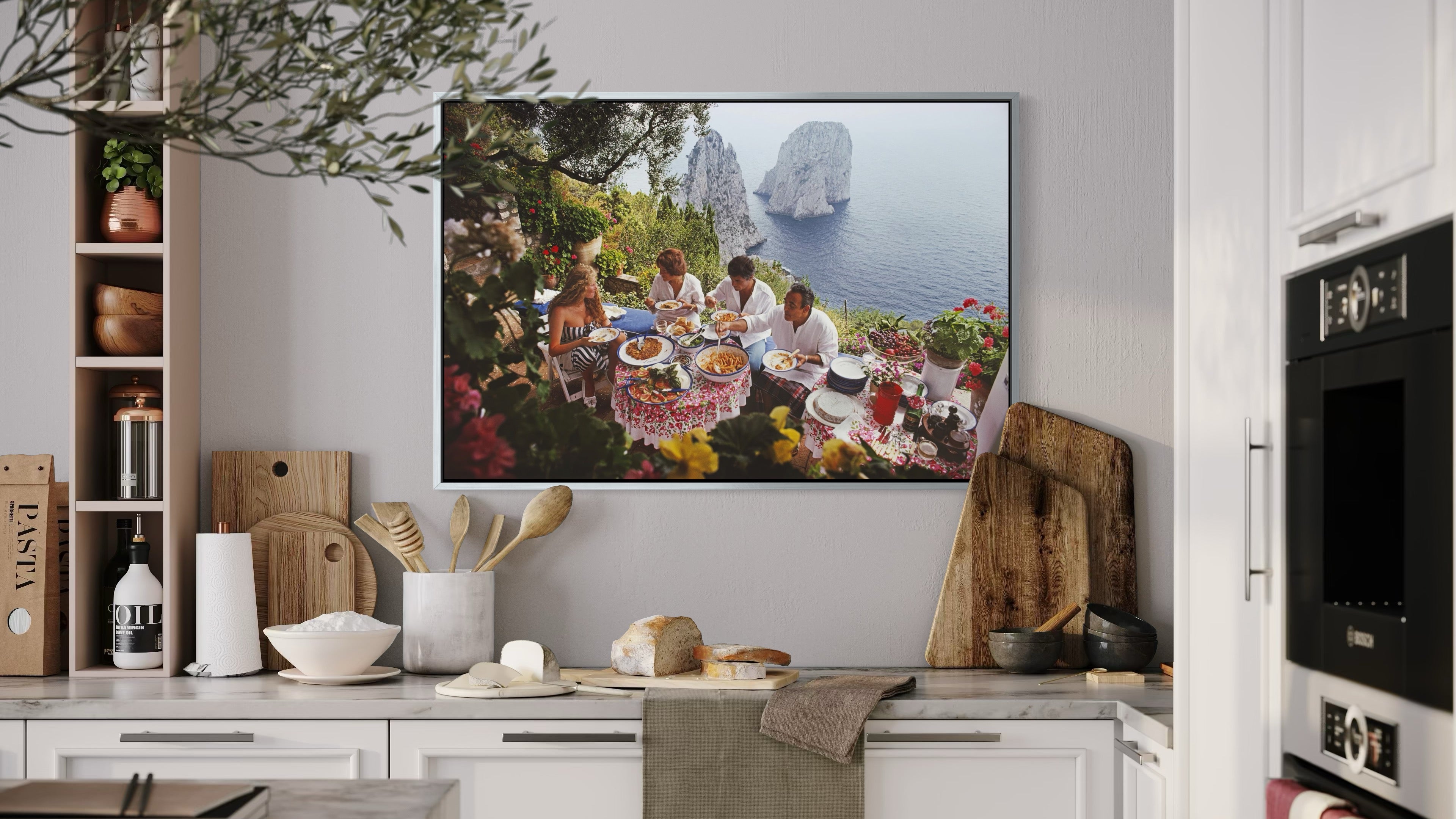 Kitchen with a TV displaying an image of people at a table with food, surrounded by nature.