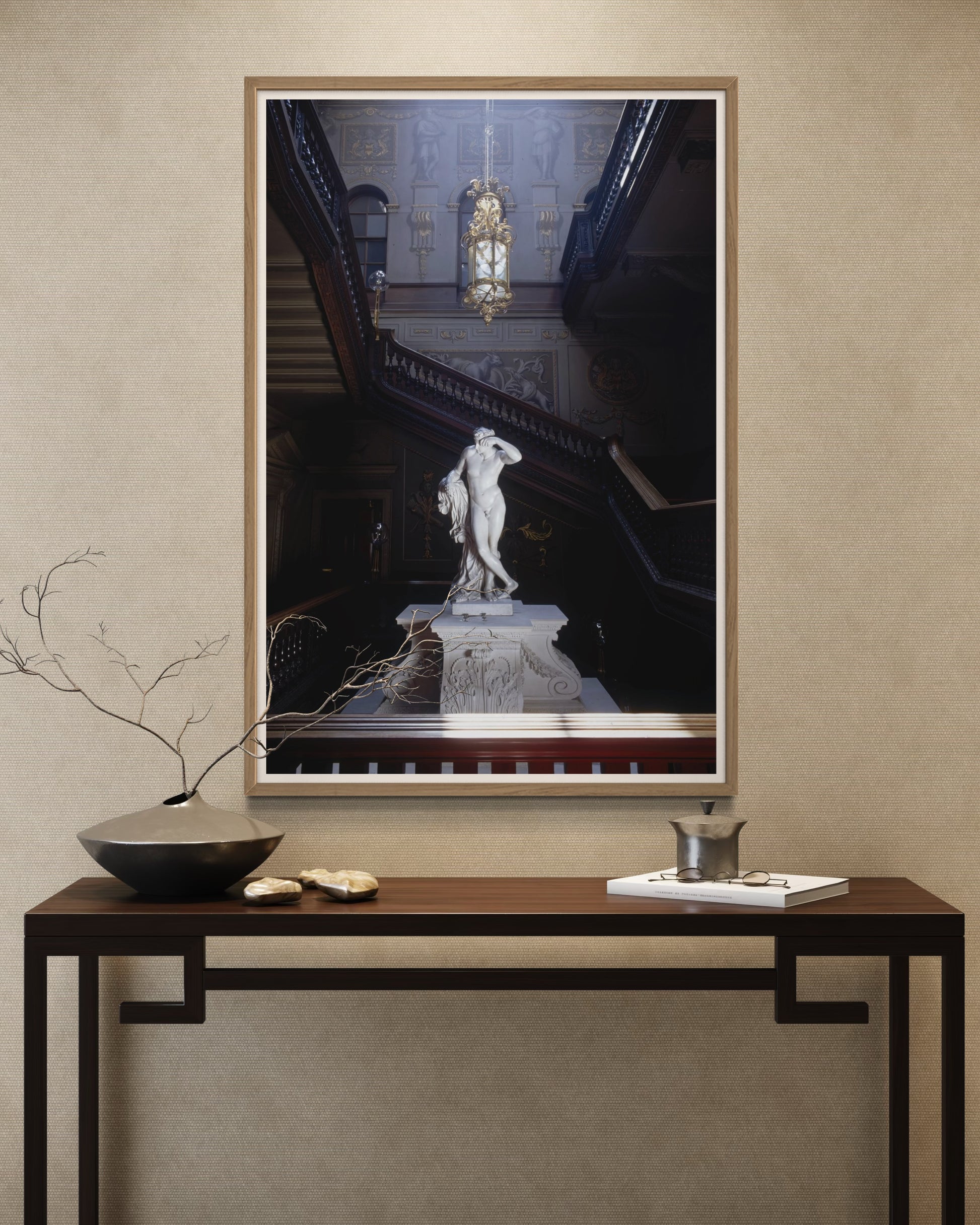 Framed artwork of a classical statue on a wall above a console table with decorative items.