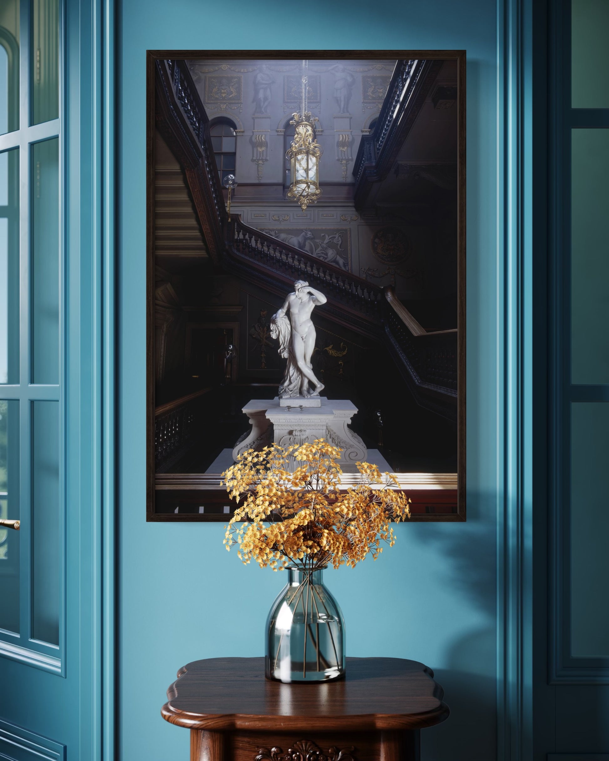 Framed artwork of a classical statue on a blue wall with a vase of flowers below.