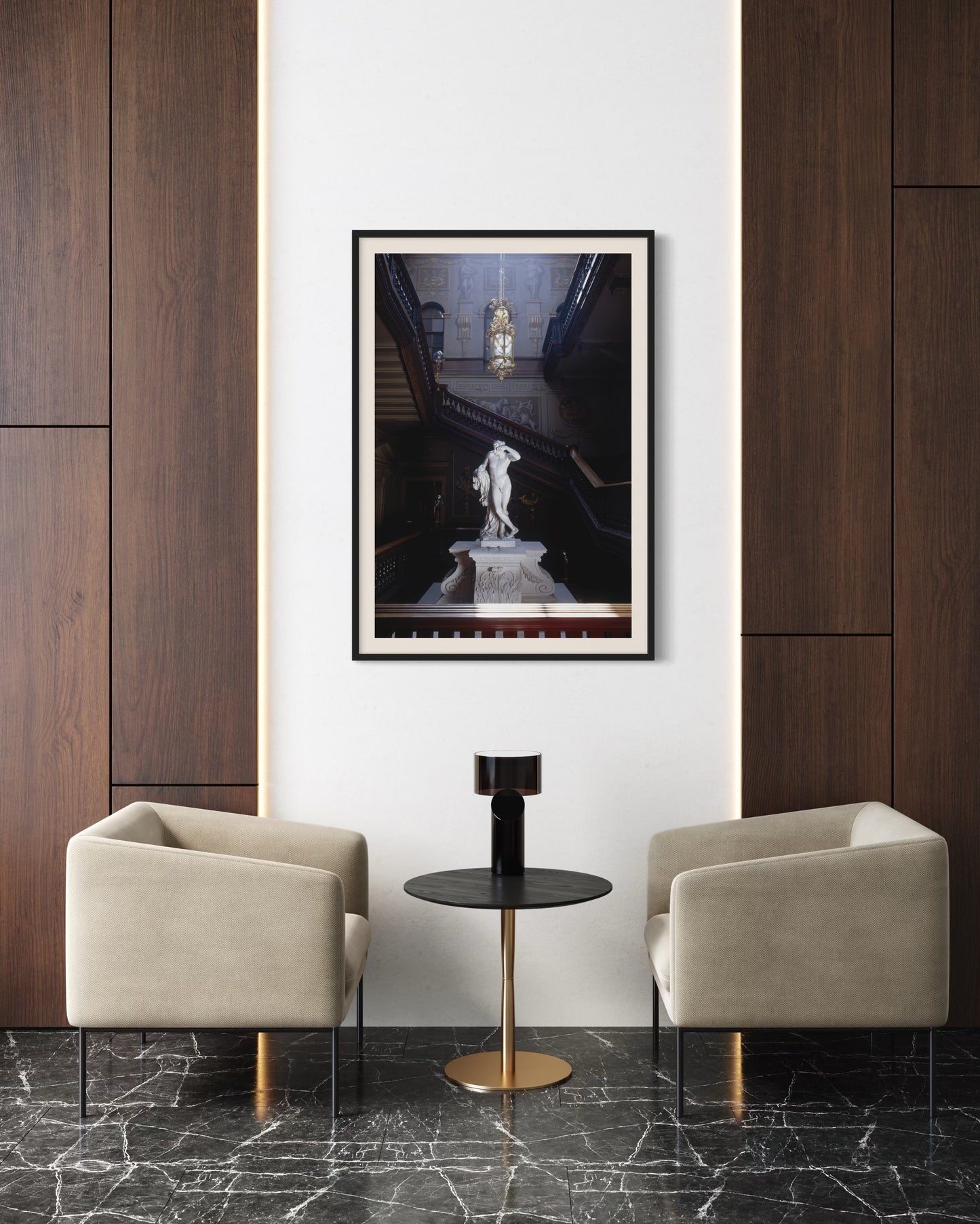 Modern interior with two beige armchairs, a small black table, and a framed picture on a white wall.