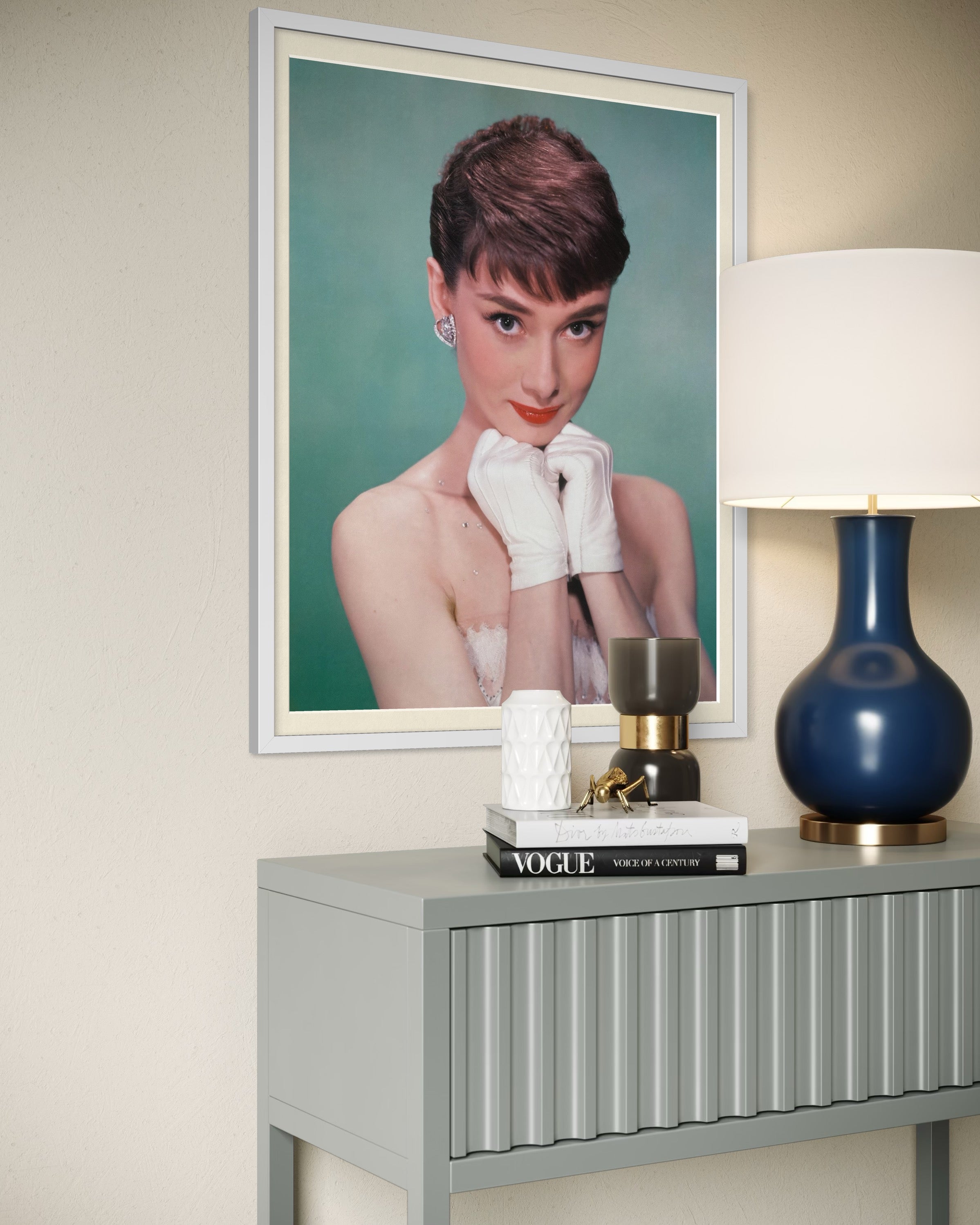 Framed portrait of audrey hepburn on a wall above a table with decorative items.