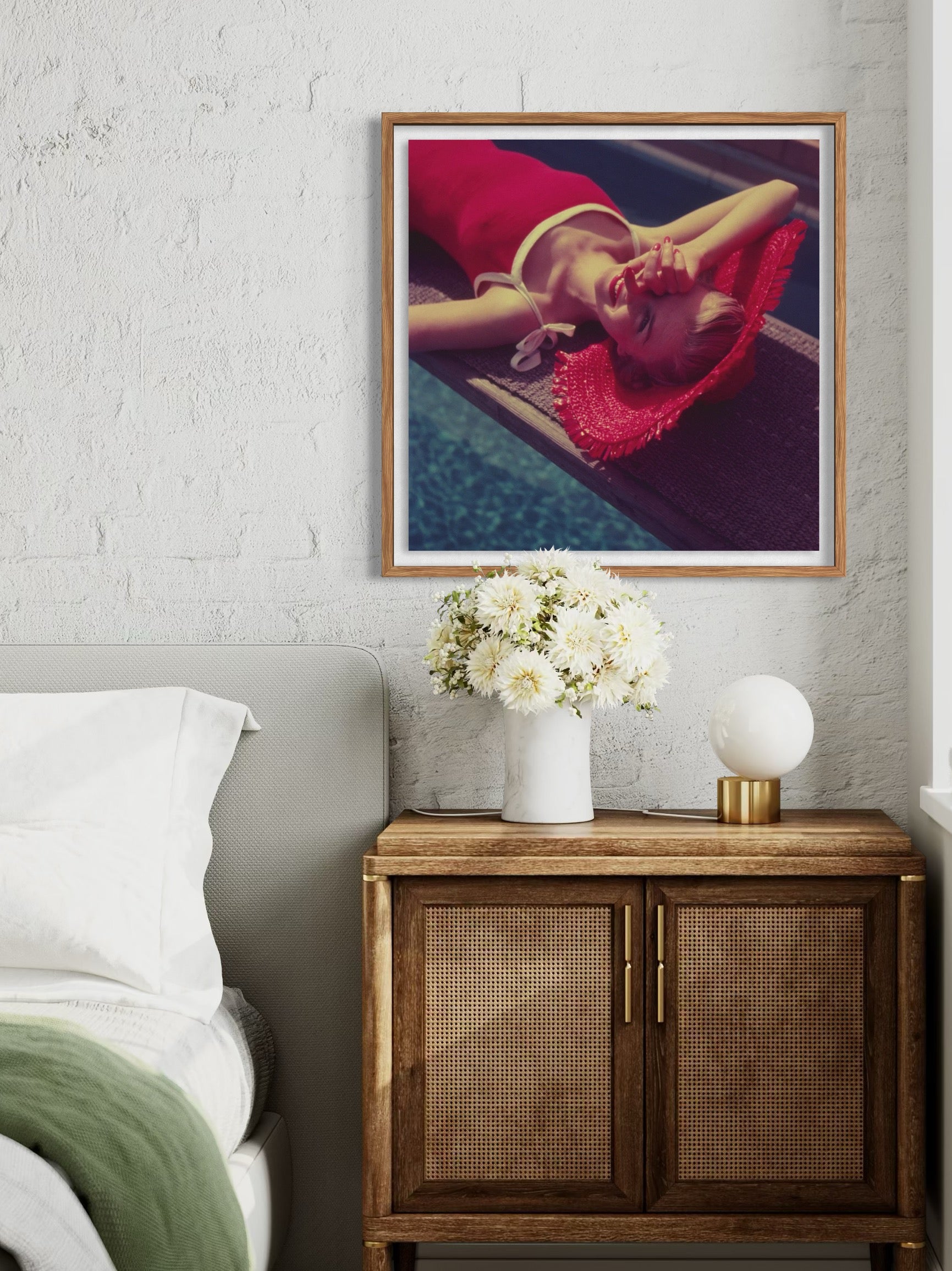 Framed artwork above a wooden cabinet with decorative items in a bedroom setting.