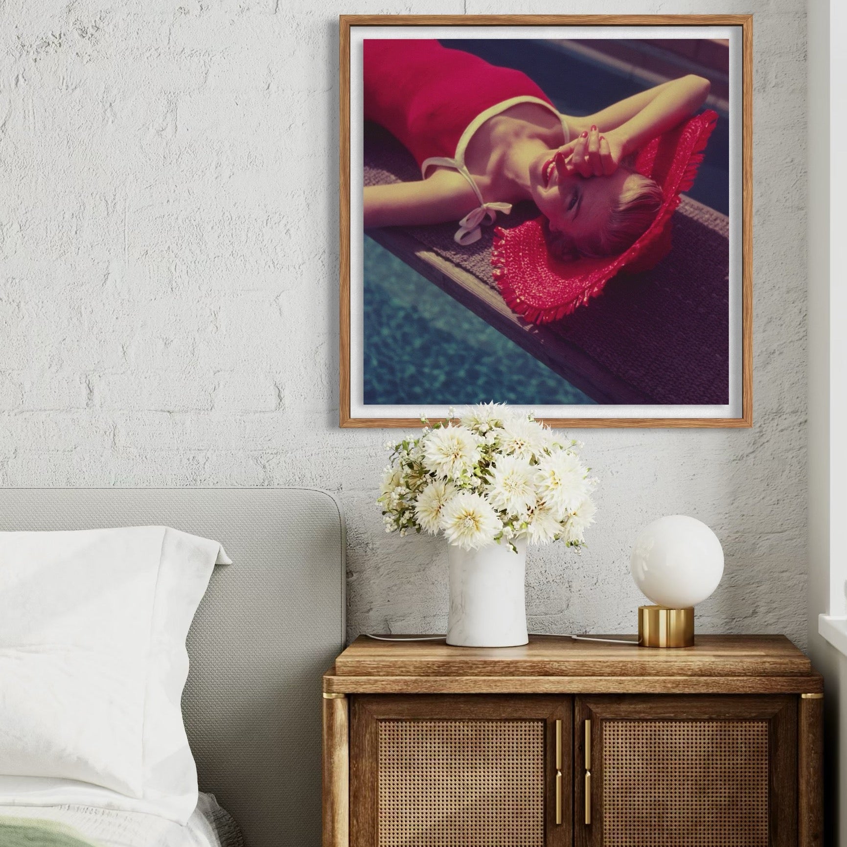 Framed artwork above a wooden cabinet with decorative items in a bedroom setting.