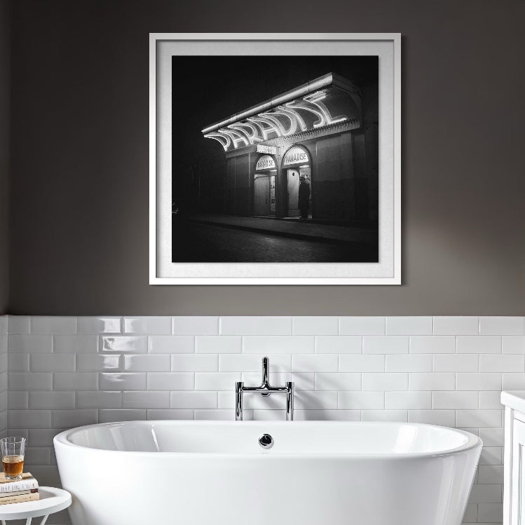 Bathroom interior with a framed black and white photograph above a freestanding bathtub.