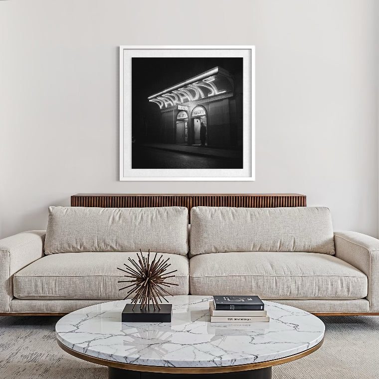 Modern living room with a beige sofa, marble coffee table, and framed black and white artwork.