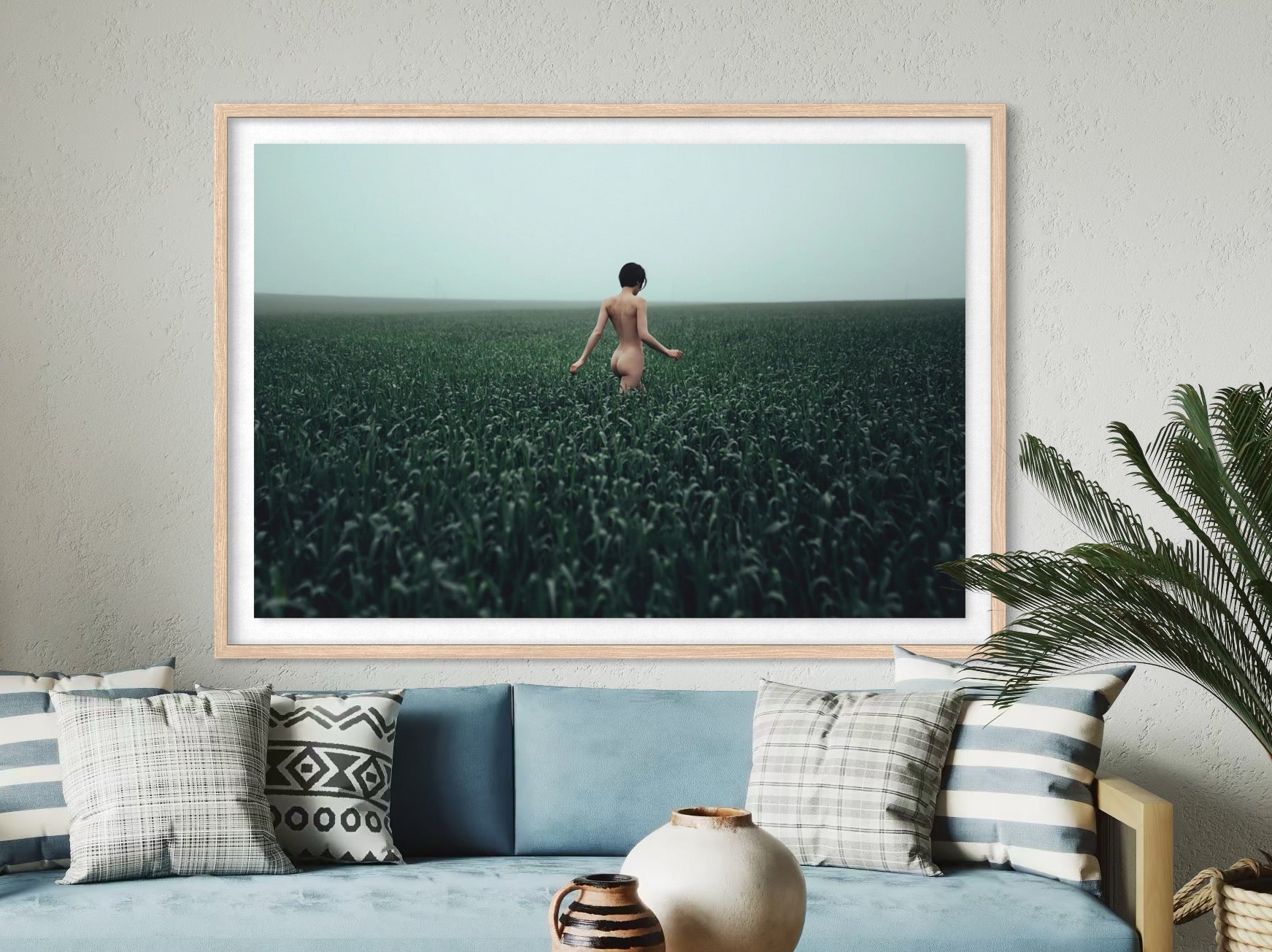 Framed artwork of a person standing in a field on a wall above a sofa.