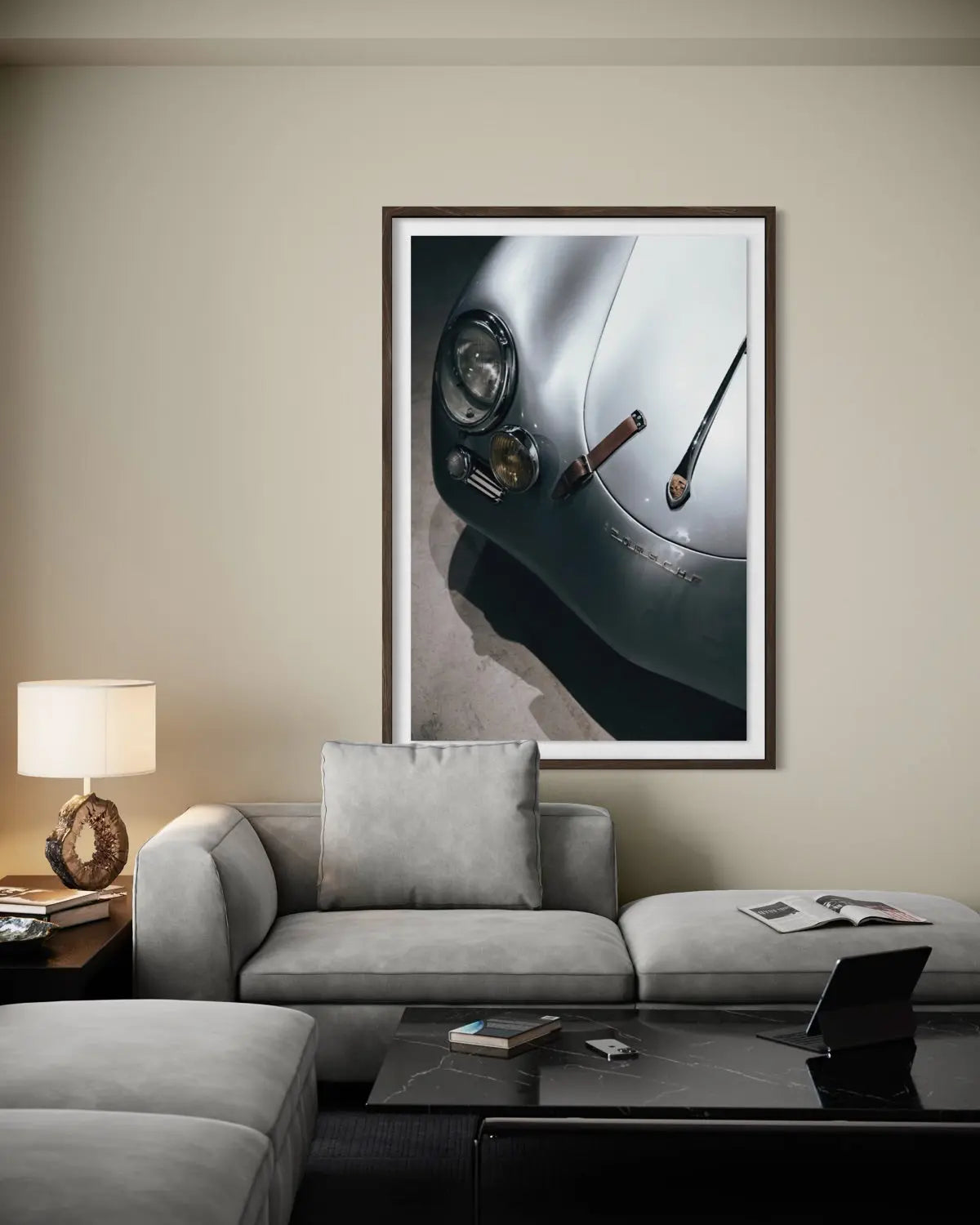 A framed wall art print depicting a close-up of a silver car's headlight and hood, styled in a modern living room setting above a gray sofa.