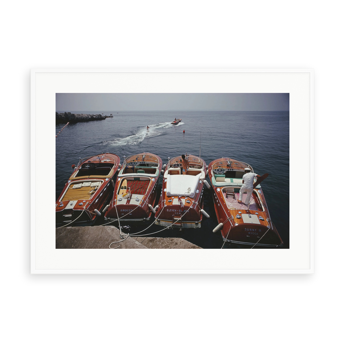 Illustrative matte-white framed preview with white inner border of Riva Boats at Hotel du Cap-Eden-Roc by Slim Aarons. Proportions vary by size.