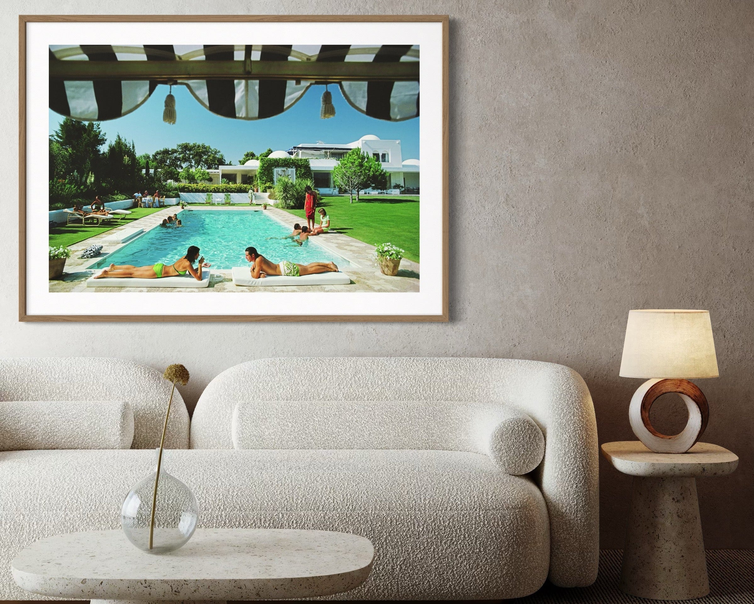 Framed artwork of a pool scene on a wall above a sofa in a living room.