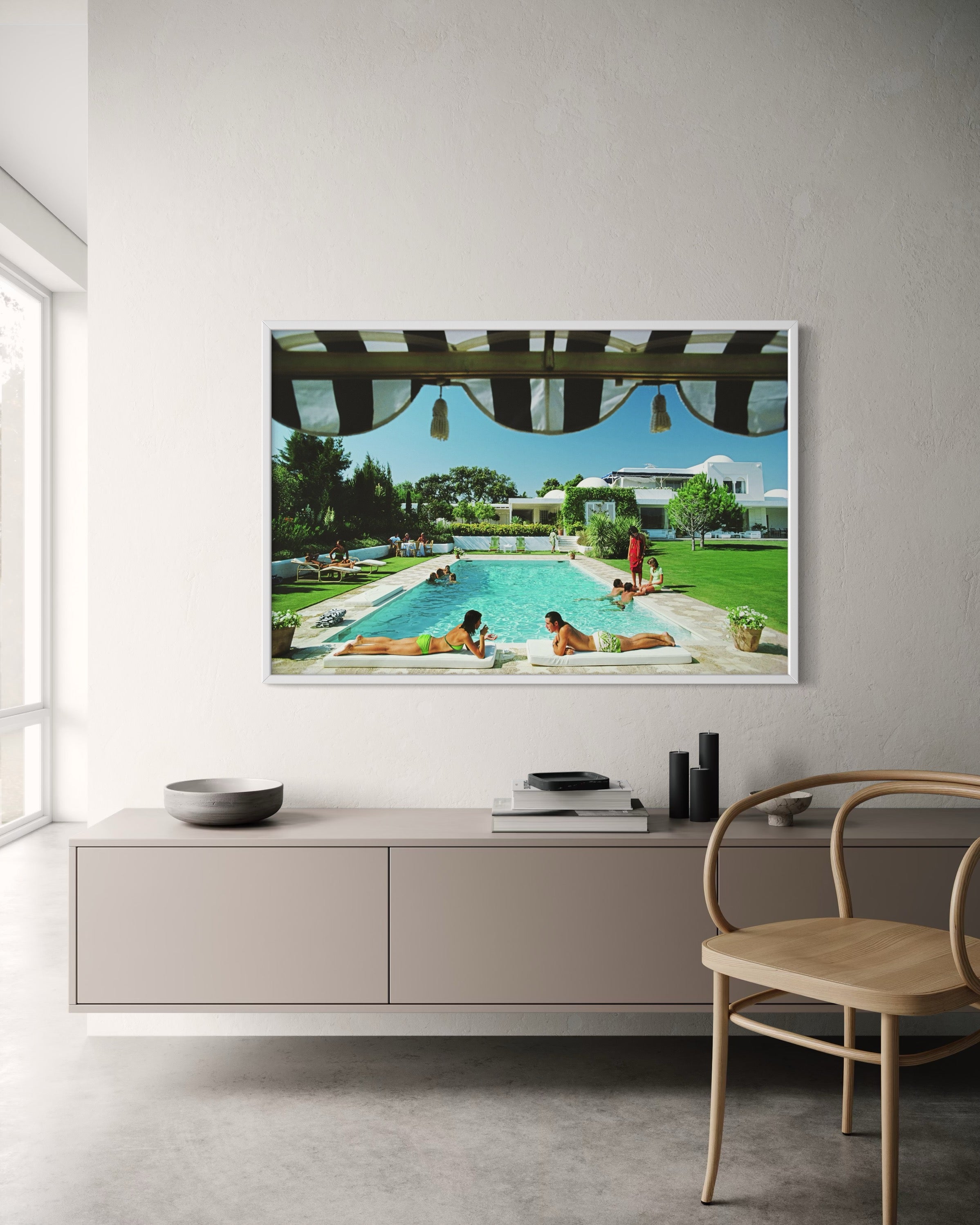 Framed artwork of a pool scene on a wall above a modern cabinet.