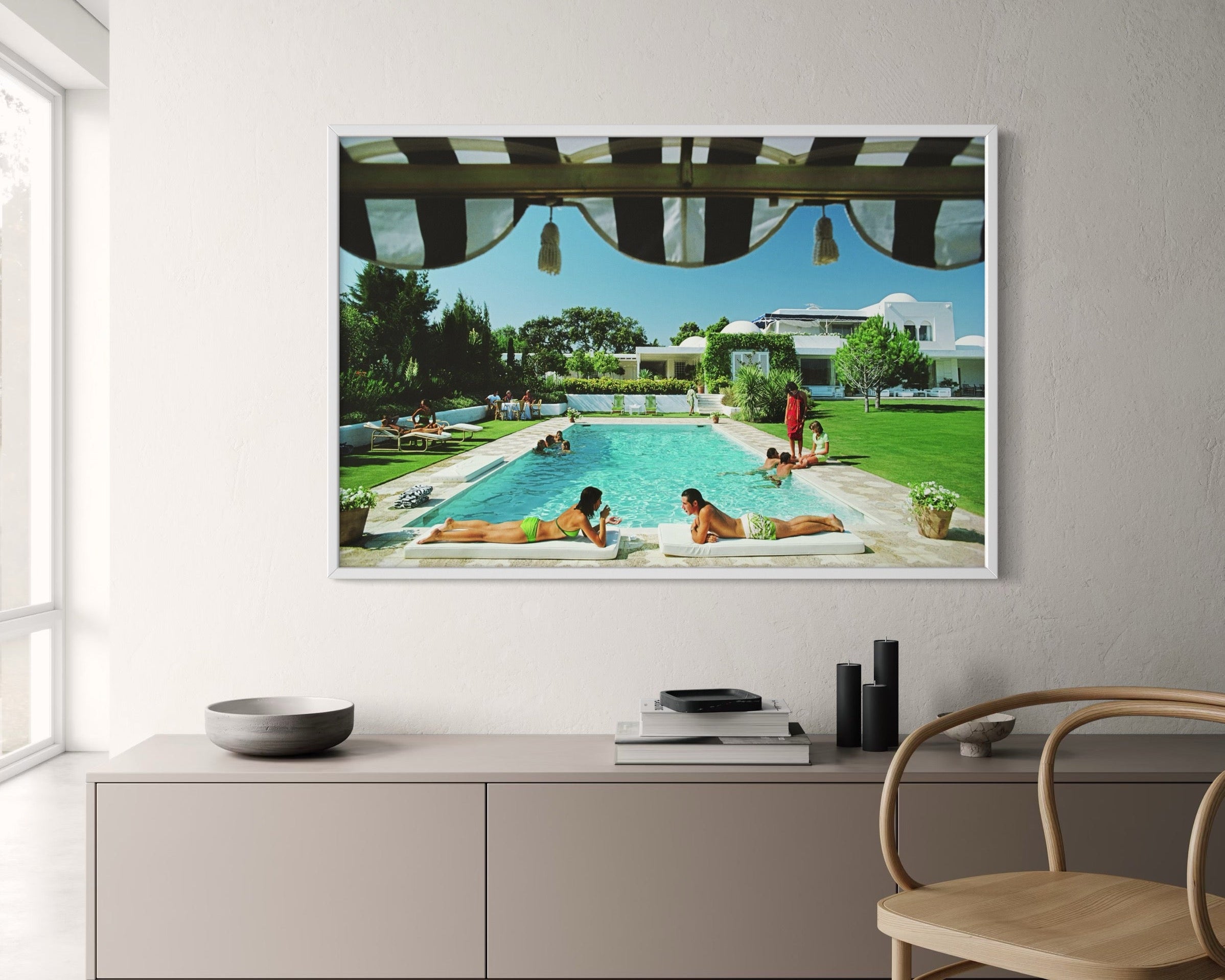 Framed artwork of a pool scene on a wall above a modern cabinet.