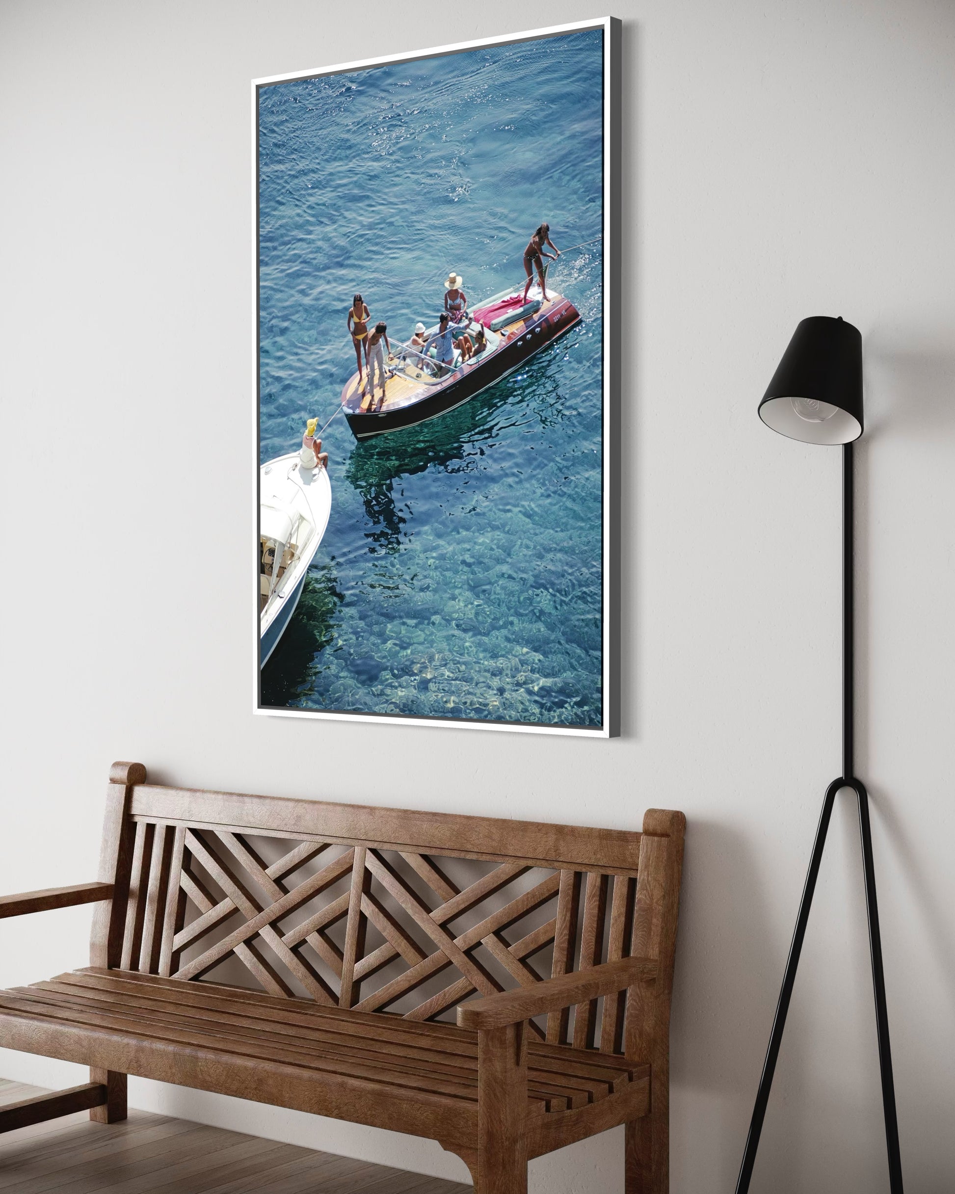 Framed photograph of people on a boat hanging on a wall above a wooden bench.