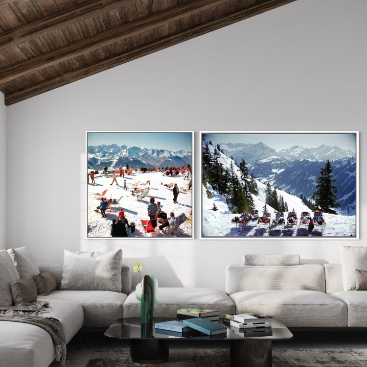Two framed pictures of snowy mountain landscapes above a white sofa in a living room.