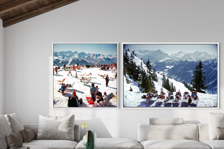 Two framed pictures of snowy mountain landscapes above a white sofa in a living room.