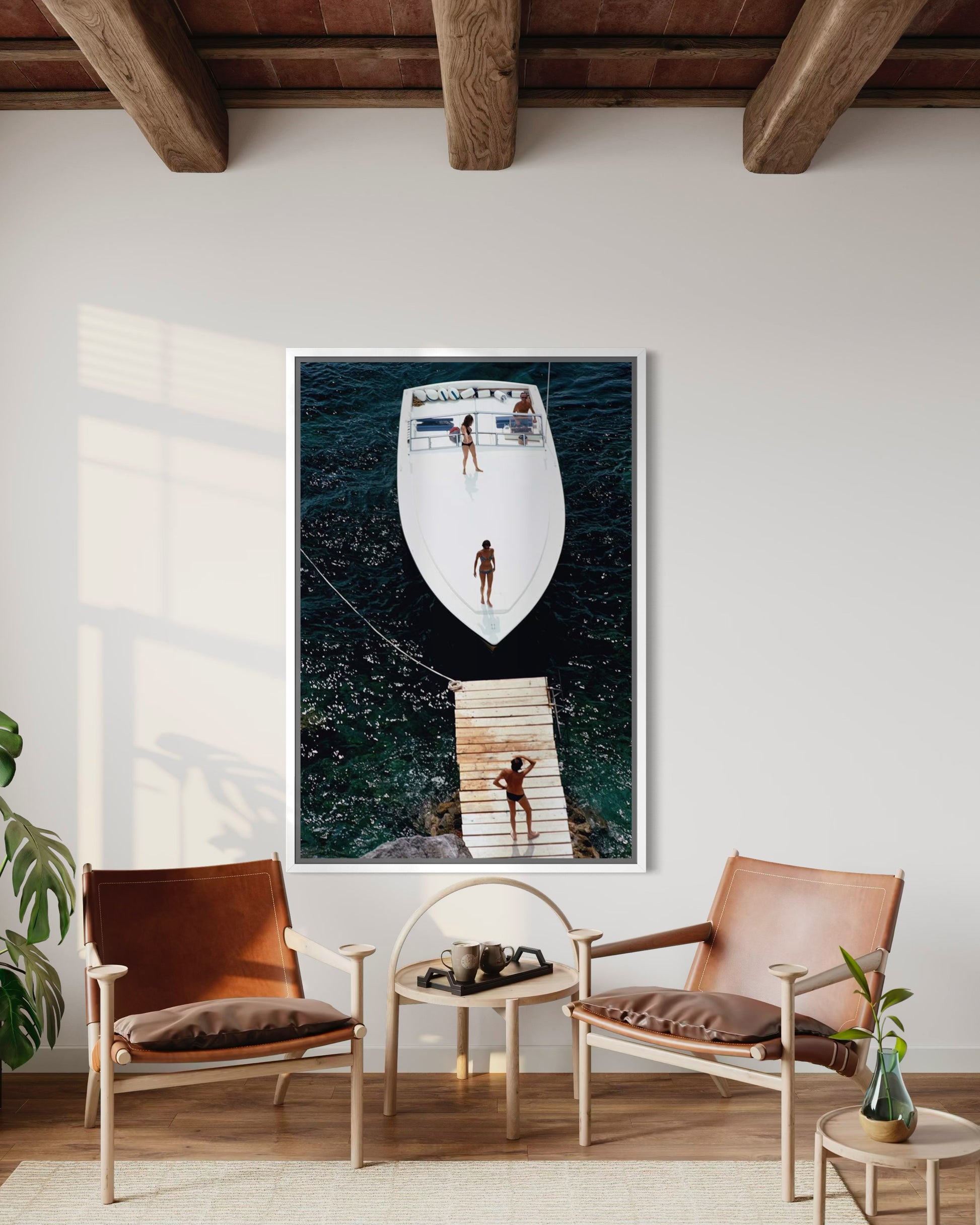 Framed artwork on a wall above a seating area with chairs and a small table.
