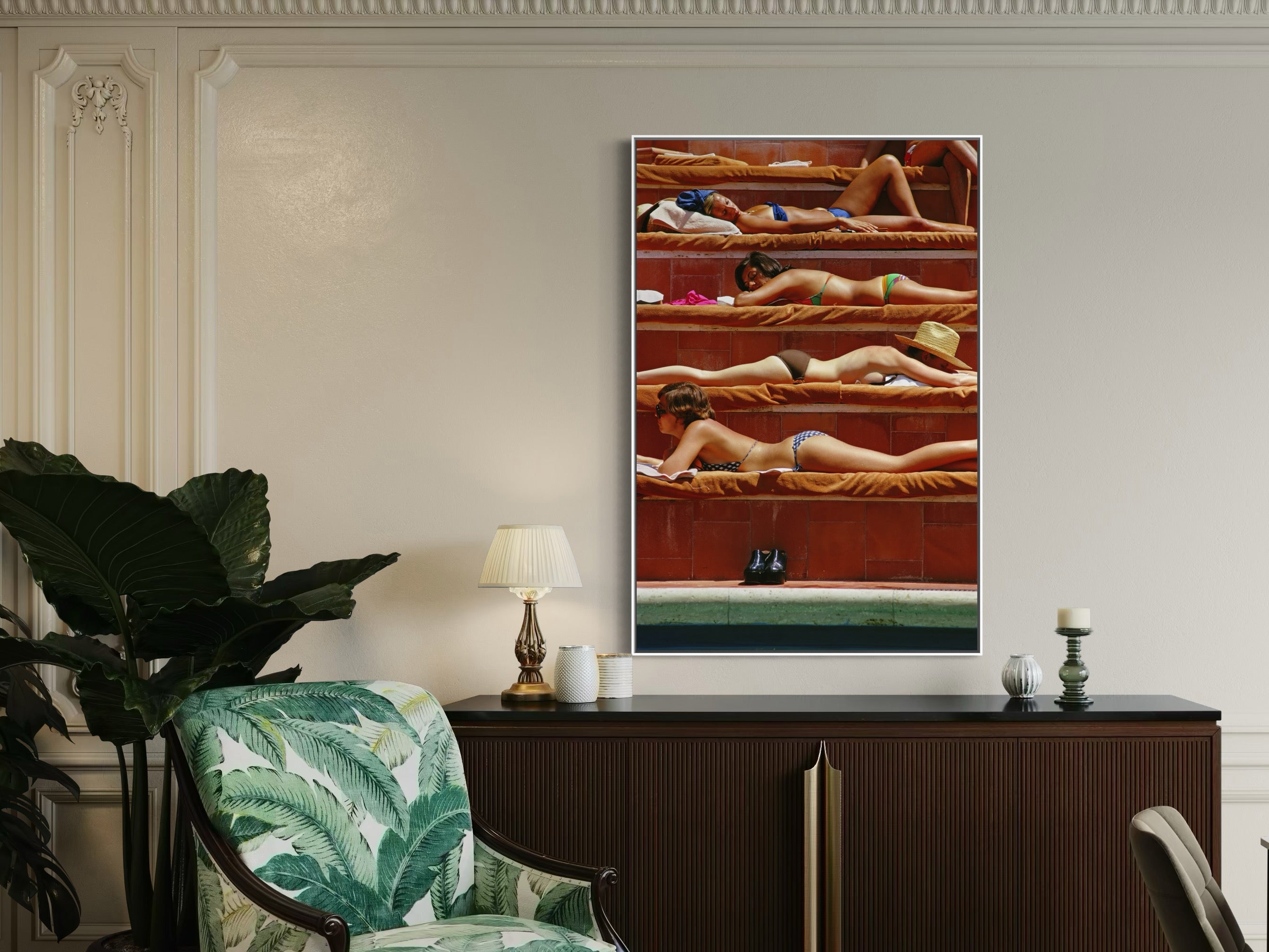 Framed artwork of people in a pool on a wall above a console table with decorative items.