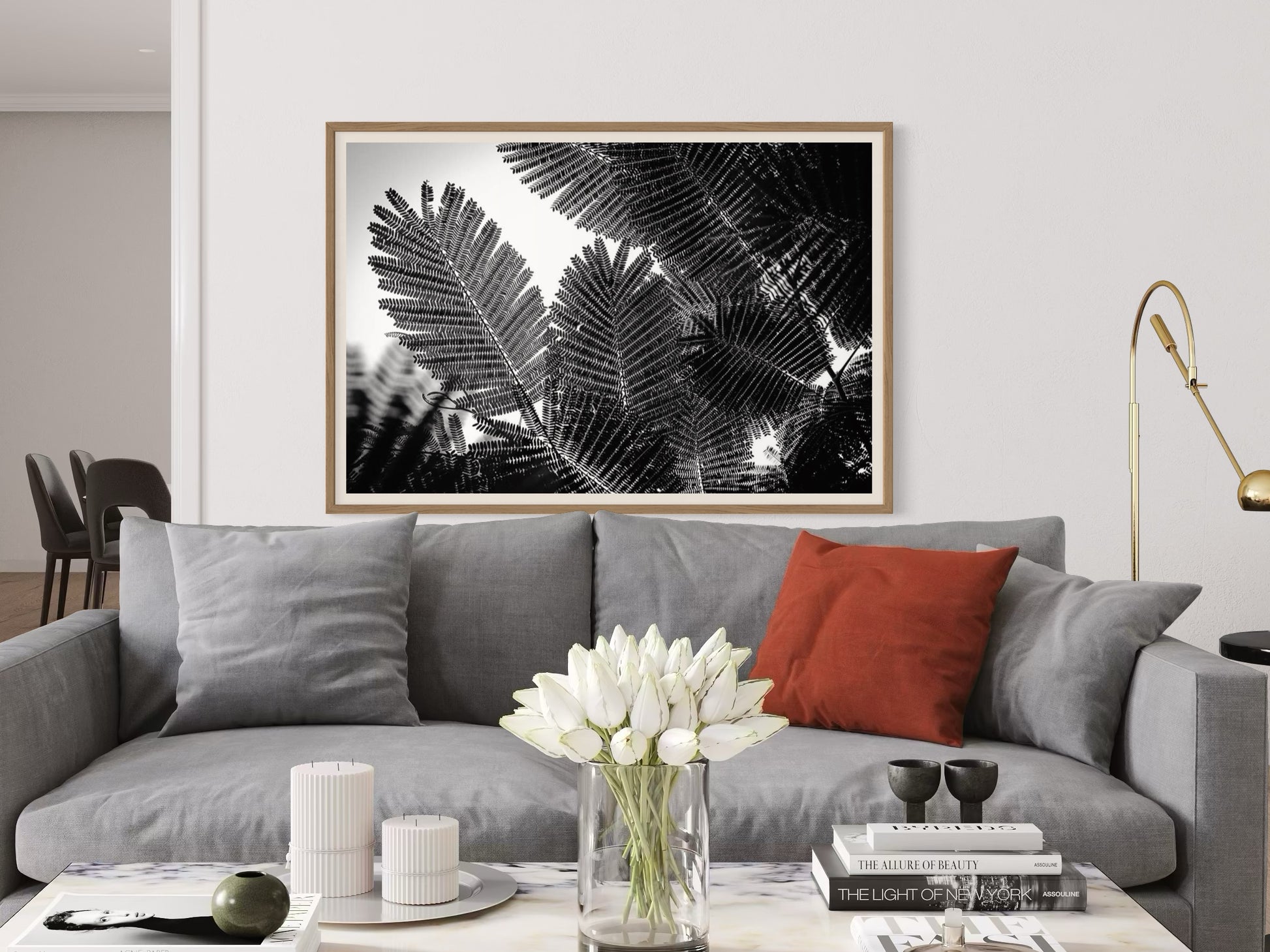 Living room with gray sofa, red pillow, and framed black and white leaf print on wall.