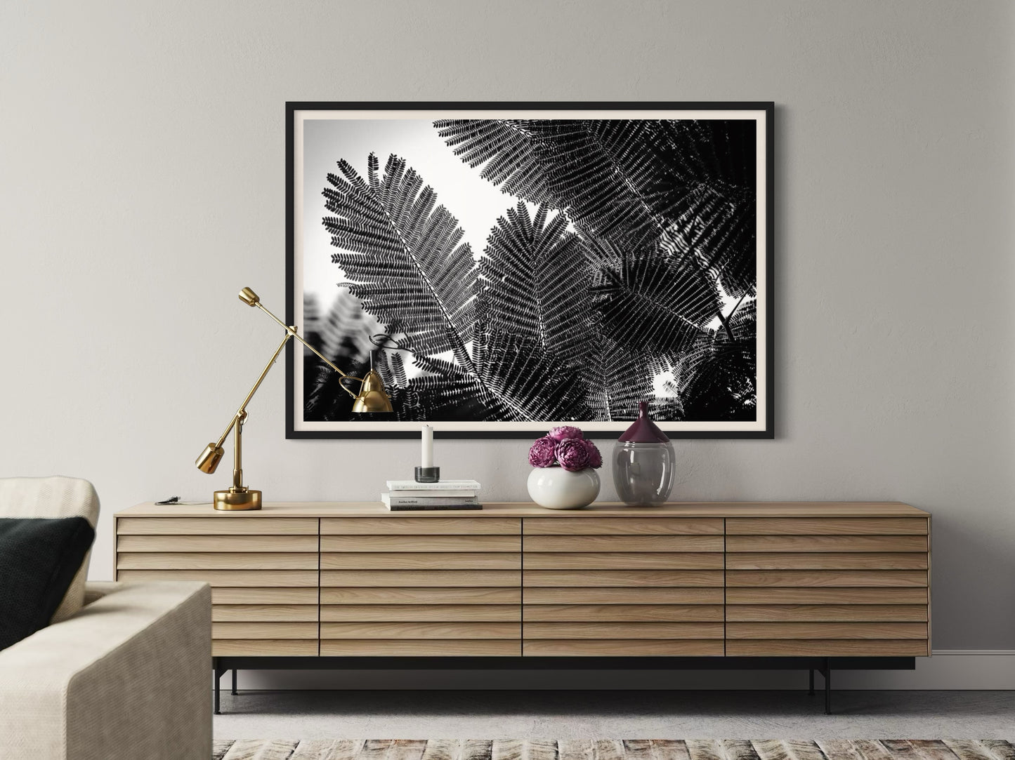 Framed black and white leaf print above a wooden console table in a living room.