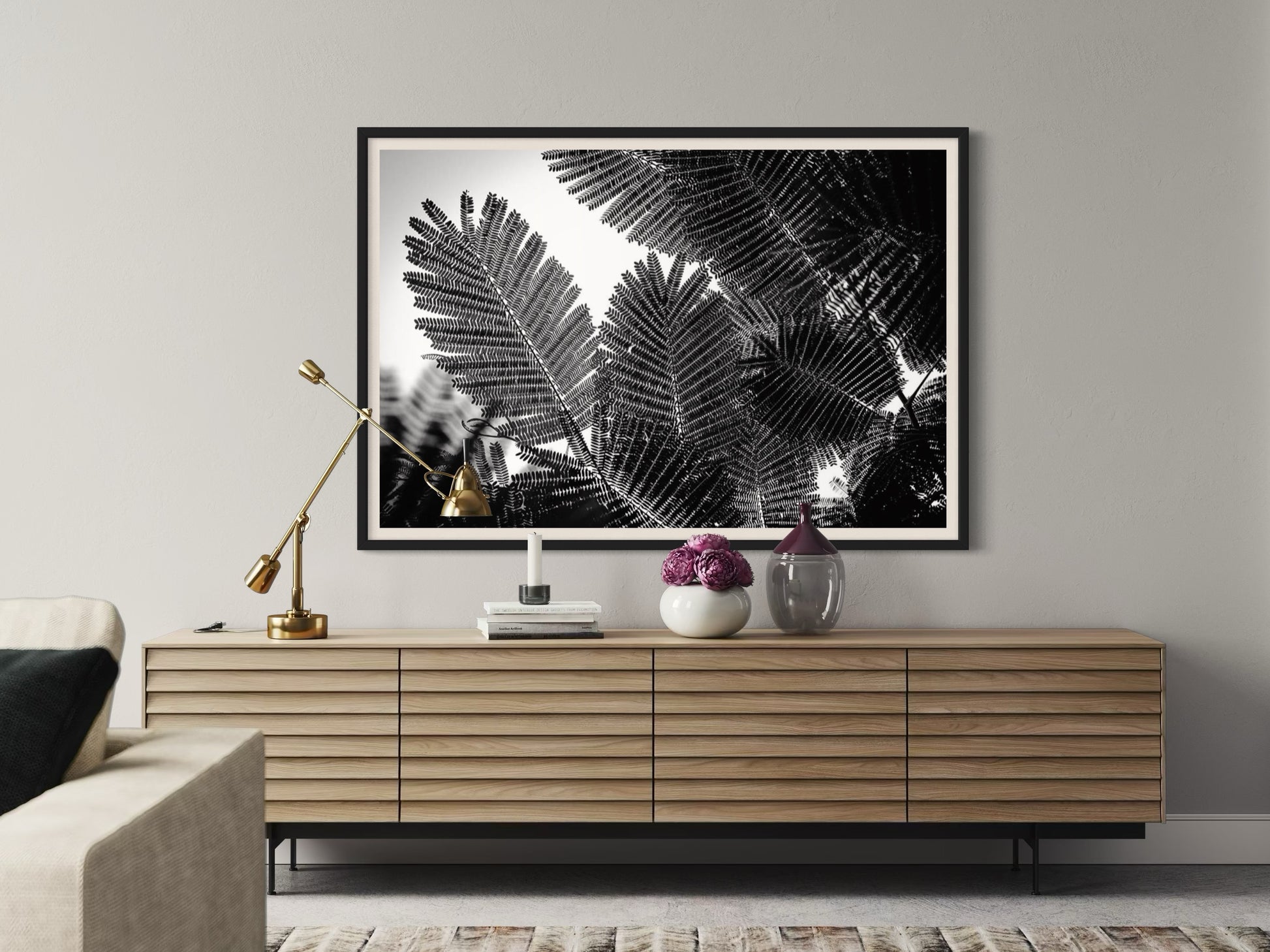Framed black and white leaf print above a wooden console table in a living room.