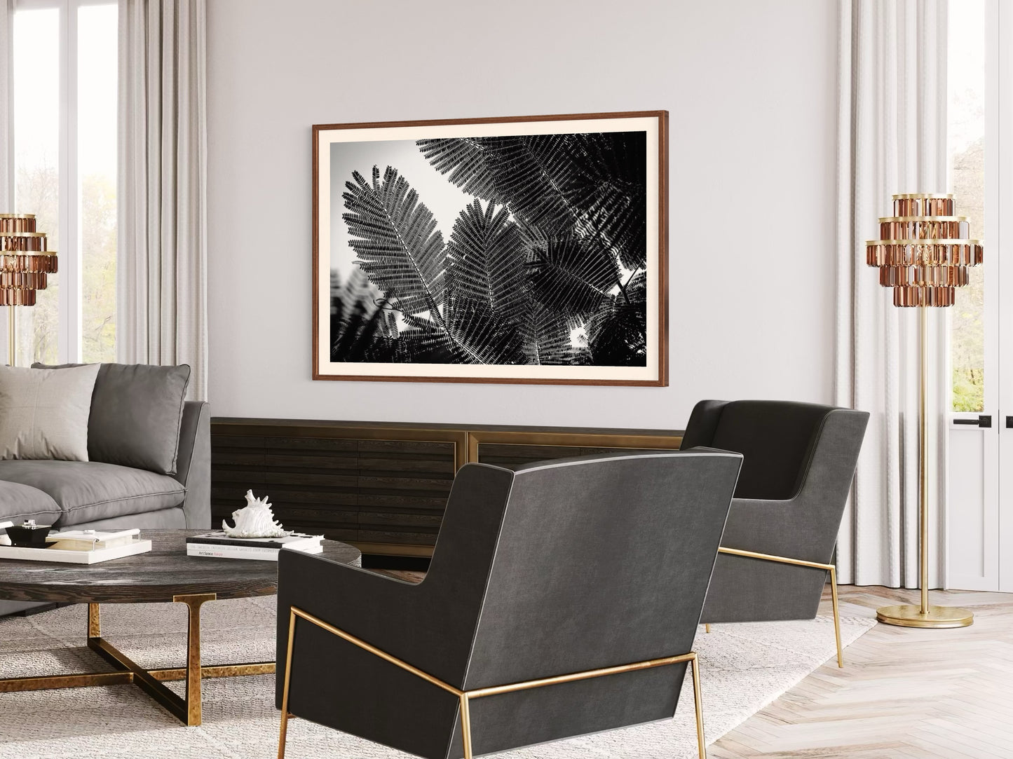 Modern living room with gray sofa, black chairs, and a framed black and white leaf print on the wall.