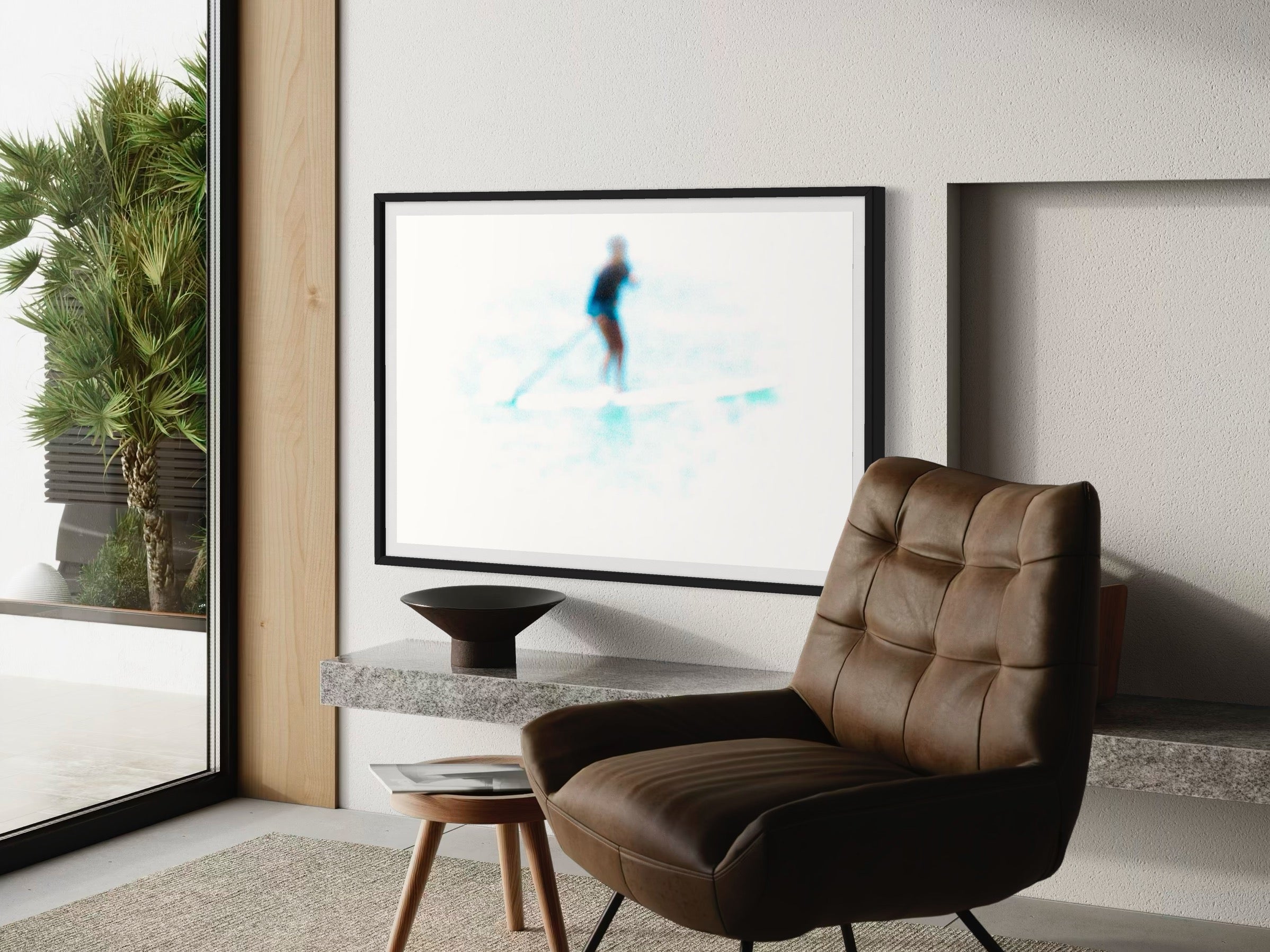 Modern living room with a brown leather chair, framed artwork, and a plant.