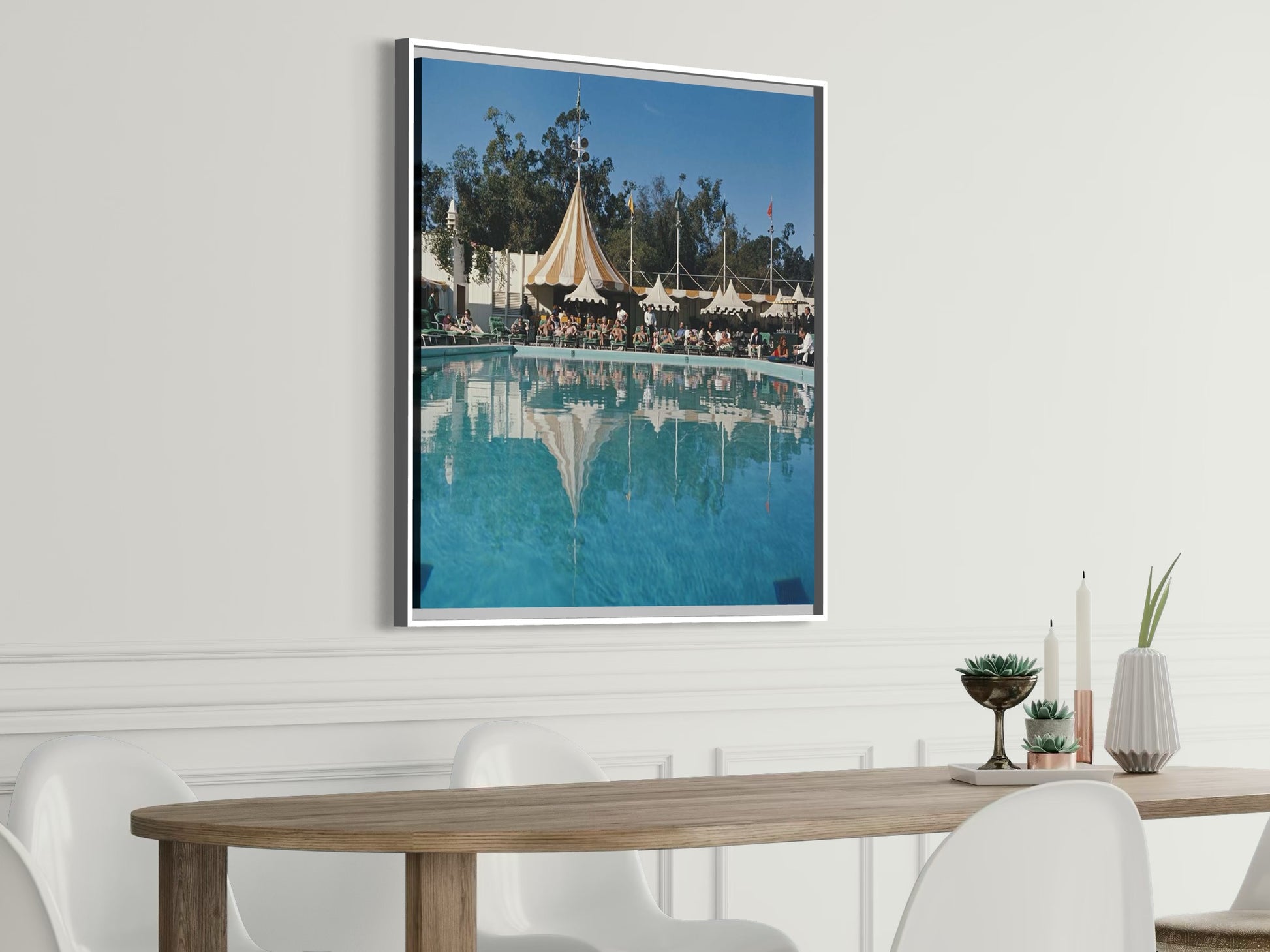 Metal print Framed photograph of a pool scene with tents on a wall above a dining table.